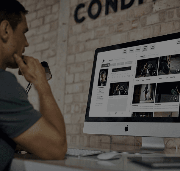 Man looking at computer screen displaying a photo gallery, with 'CONDITION & PERFORM' visible on the wall behind.